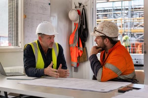 Construction site manager and supervisor discussing psychosocial WHS issues in a temporary site office